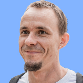 I'm Aleksandr Verevkin (alexandrverevkin.com) and I'm pictured here with long hair on my beard on which have one ponytails braided with hair bands. I'm wearing a hat with a strange, indecipherable writing on my head. I smile with my mouth open and shout something at the same time, while squinting into the distance. I'm wearing a shirt, a fleece, a T-shirt, and a long-sleeve hooded sweatshirt. The photo is in black, the background is replaced with blue, this is the style of UNICORN WITNESSES brand (unicornwitnesses.com)