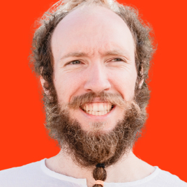 I'm Aleksey Dolgih (alexdolbun.com) and I'm pictured here with long hair on my beard on which have two ponytails braided with hair bands. I'm wearing a panama with a strange, indecipherable writing on my head. I smile with my mouth open and shout something at the same time, while squinting into the distance. I'm wearing a shirt, a fleece, a T-shirt, and a long-sleeve hooded sweatshirt. The photo is in black, the background is replaced with red, this is the style of UNICORN WITNESSES brand (unicornwitnesses.com)